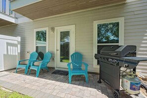 A patio with two Adirondack chairs, a grill, and a propane tank. - The Coastal Drift Communal Pool (Miramar Beach)