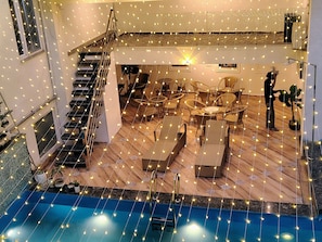Amplio espacio interior con piscina, sillas de descanso y una escalera.