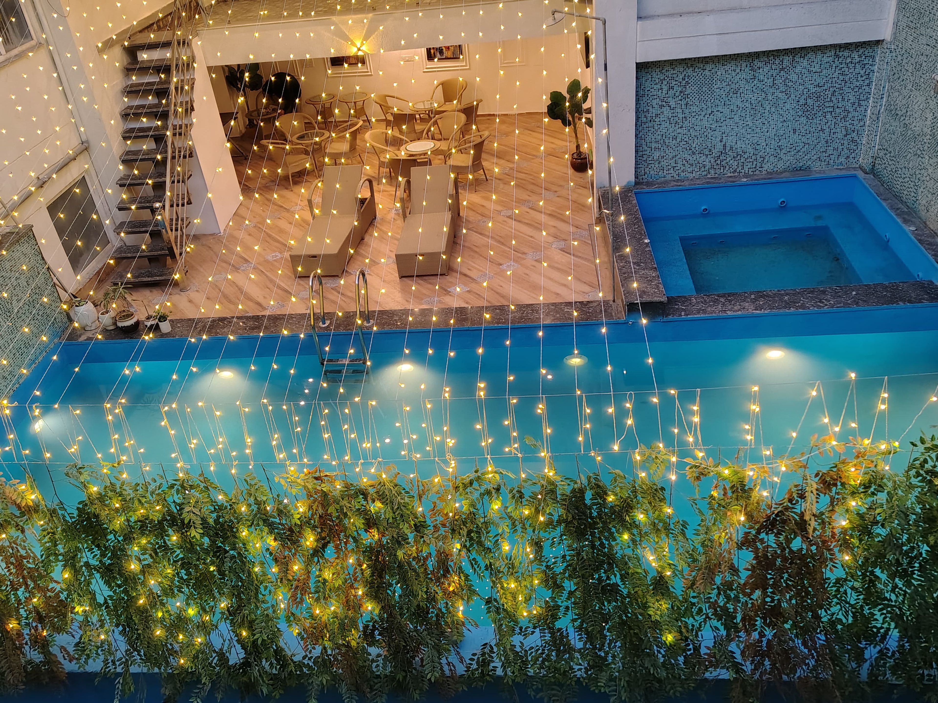 A pool area with string lights and lounge chairs.