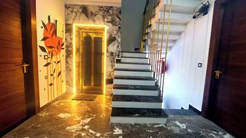 Un pasillo con piso de mármol que conduce a una escalera de diseño moderno.