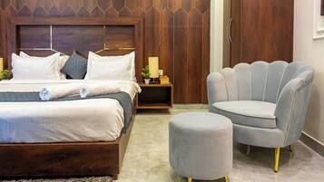 Un dormitorio con cama, mesitas de noche, lámpara, silla y reposapiés.
