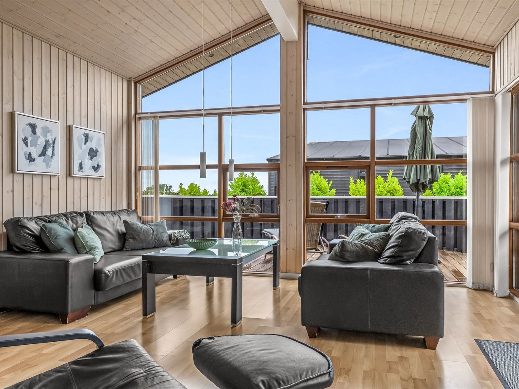 A spacious living room with a large window, a sofa, a coffee table, and artwork on the wall.