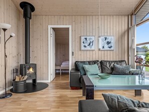 Ein modernes Wohnzimmer mit Kaminofen, Glastisch und Ledersofa.
