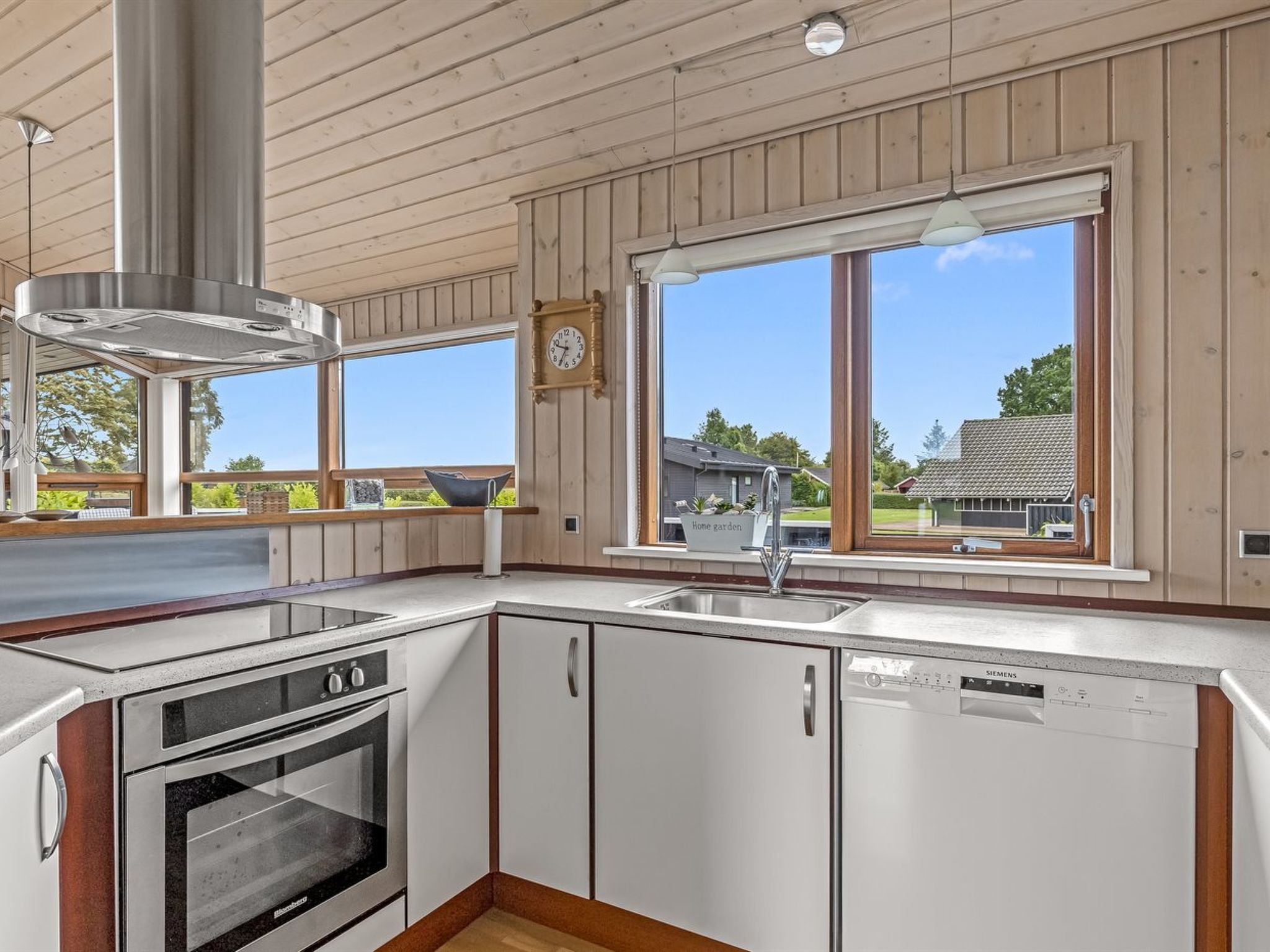 Eine moderne Küche mit großem Fenster, Edelstahlgeräten und Holzschränken.
