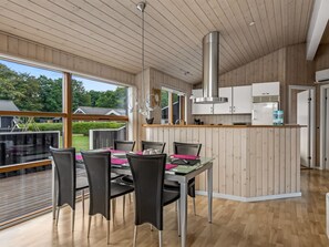 Eine moderne Küche mit einer zentralen Kochinsel, Holzböden und großen Fenstern mit Blick ins Freie.