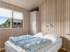 A bedroom with a bed, a window, wooden walls, and a view of a house outside. - "Thrine" - 150m from the sea by Interhome (Sjølund)