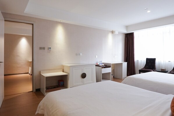 A hotel room with two beds, a desk, a chair, and a window with curtains.