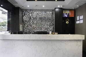 A reception desk with a marble top, a decorative wall with circular patterns, and a digital screen displaying information. - Paco Hotel (Guangzhou Tianhe Coach Terminal Metro Station) (Guangzhou)