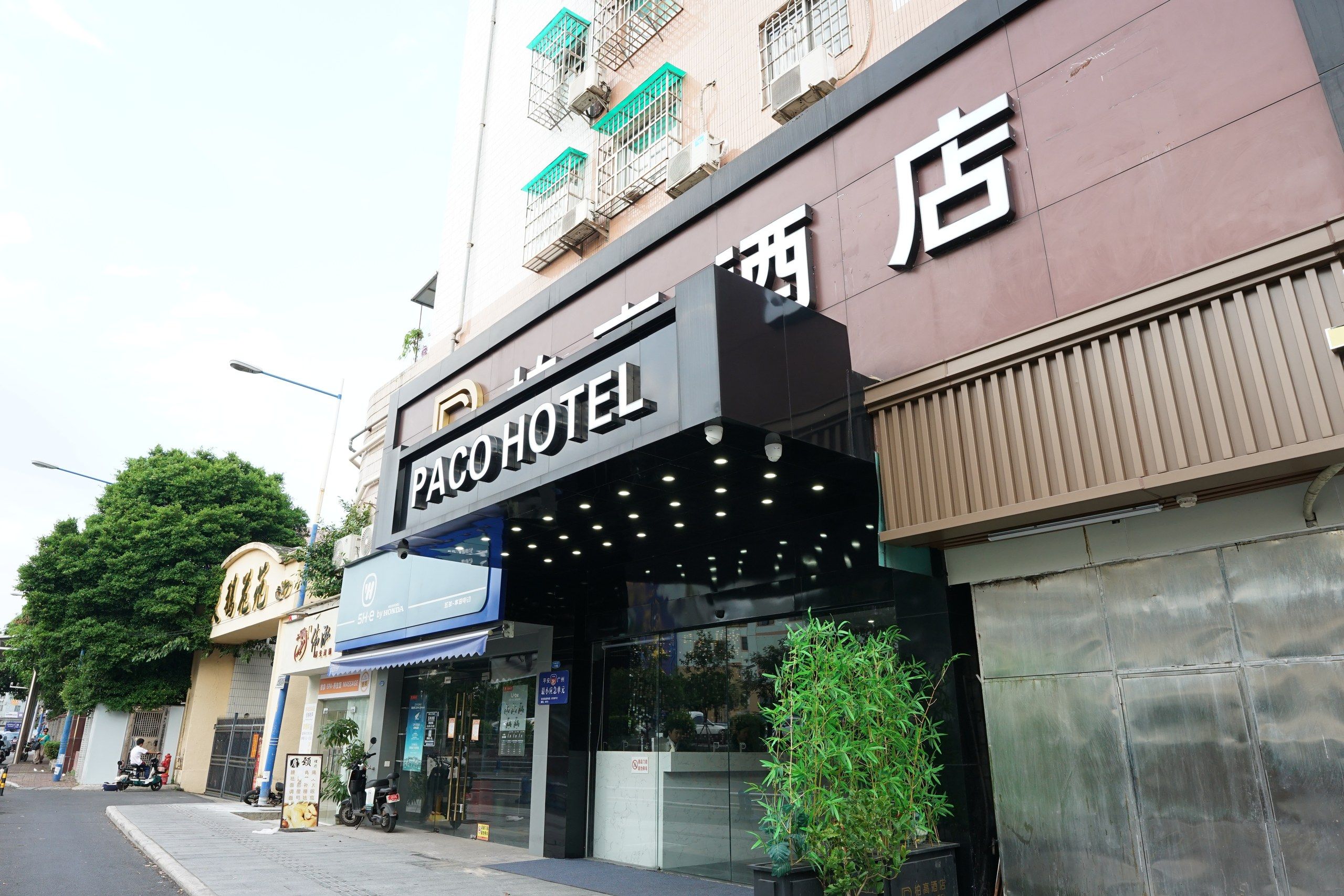 Fachada de hotel com uma placa indicando 'PACOTEL' e uma entrada visível.