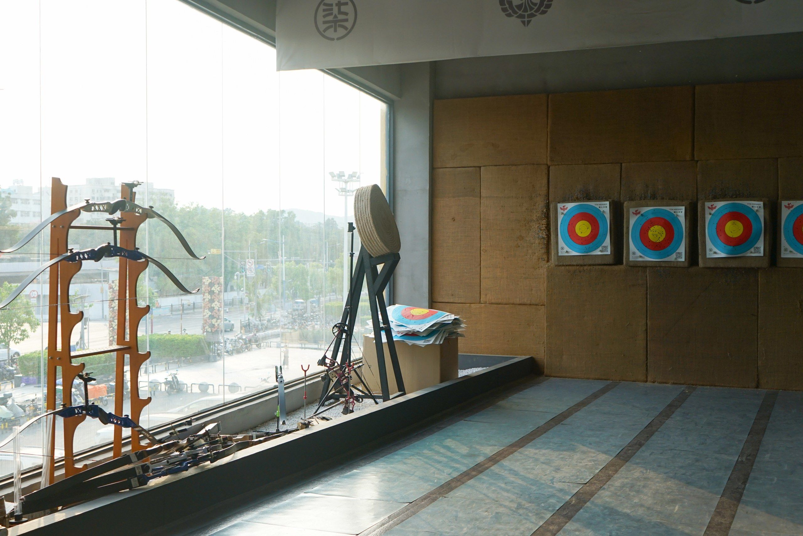 An indoor archery range with targets, a bow, and a quiver.
