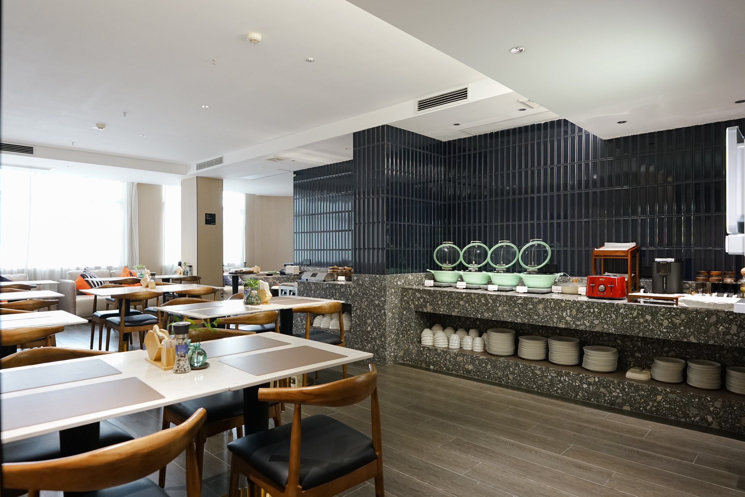 A modern restaurant with a counter, seating, and a kitchen area.