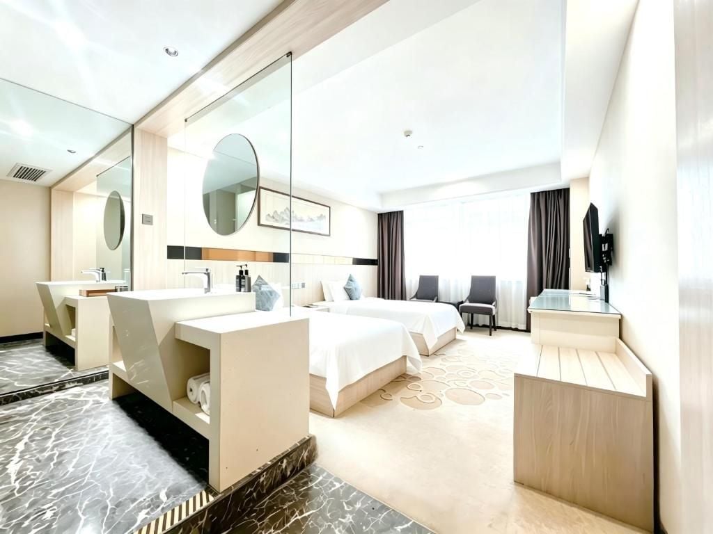 Een hotelkamer met een groot bed, een eigen badkamer met wastafel, een flatscreen televisie en een groot raam.