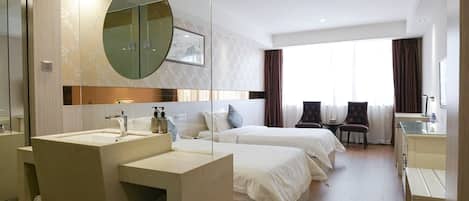 Une chambre d’hôtel avec un grand miroir, deux lits, un bureau et une salle de bain équipée d’un lavabo et d’un espace pour ranger les serviettes.