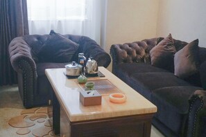 A living room with a sofa, a coffee table, and a kettle.