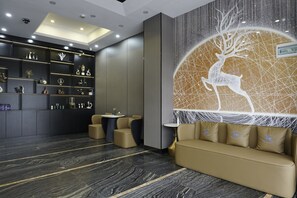 Un vestíbulo moderno con un sofá, una mesa de centro y una pared decorativa con diseño geométrico.