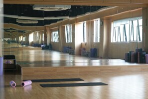 A spacious dance studio with wooden floors, large mirrors, and exercise mats.