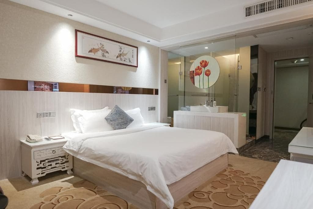 Ein Hotelzimmer mit Bett, Nachttisch und Spiegel mit floralem Dekor.