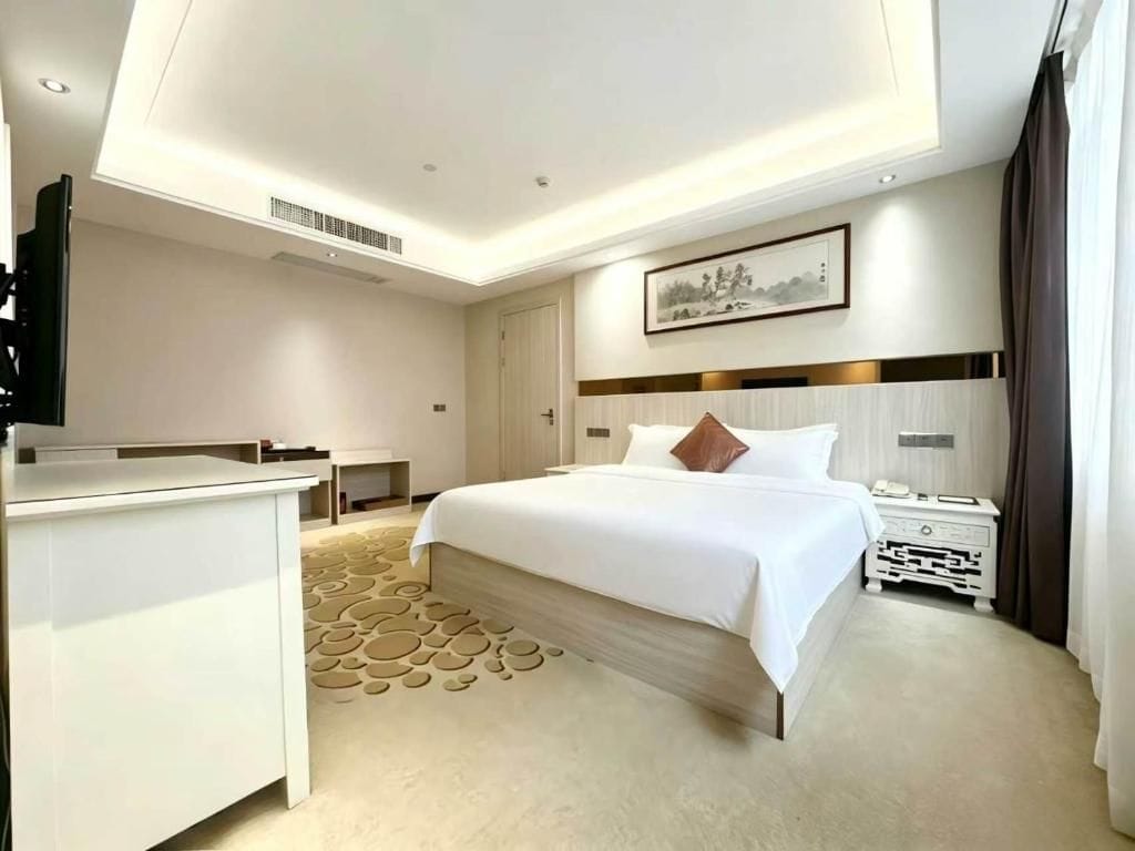 Una habitación de hotel moderna con una cama grande, un escritorio y un televisor de pantalla plana.
