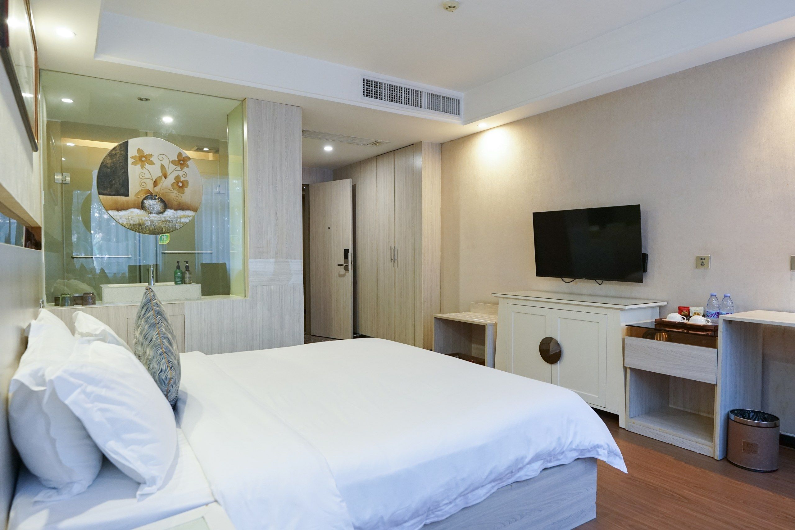 Una habitación de hotel con una cama, televisión, un escritorio pequeño y un espejo.