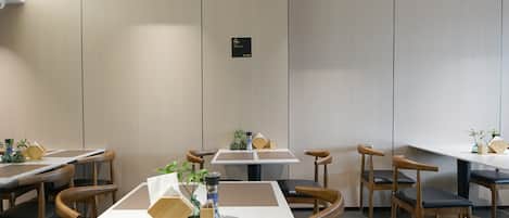 A modern dining area with multiple tables and chairs, a no-smoking sign, and a clean, minimalist design.