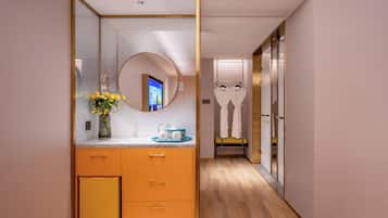 Un baño moderno con tocador, espejo y una pequeña zona de estar con toallas.