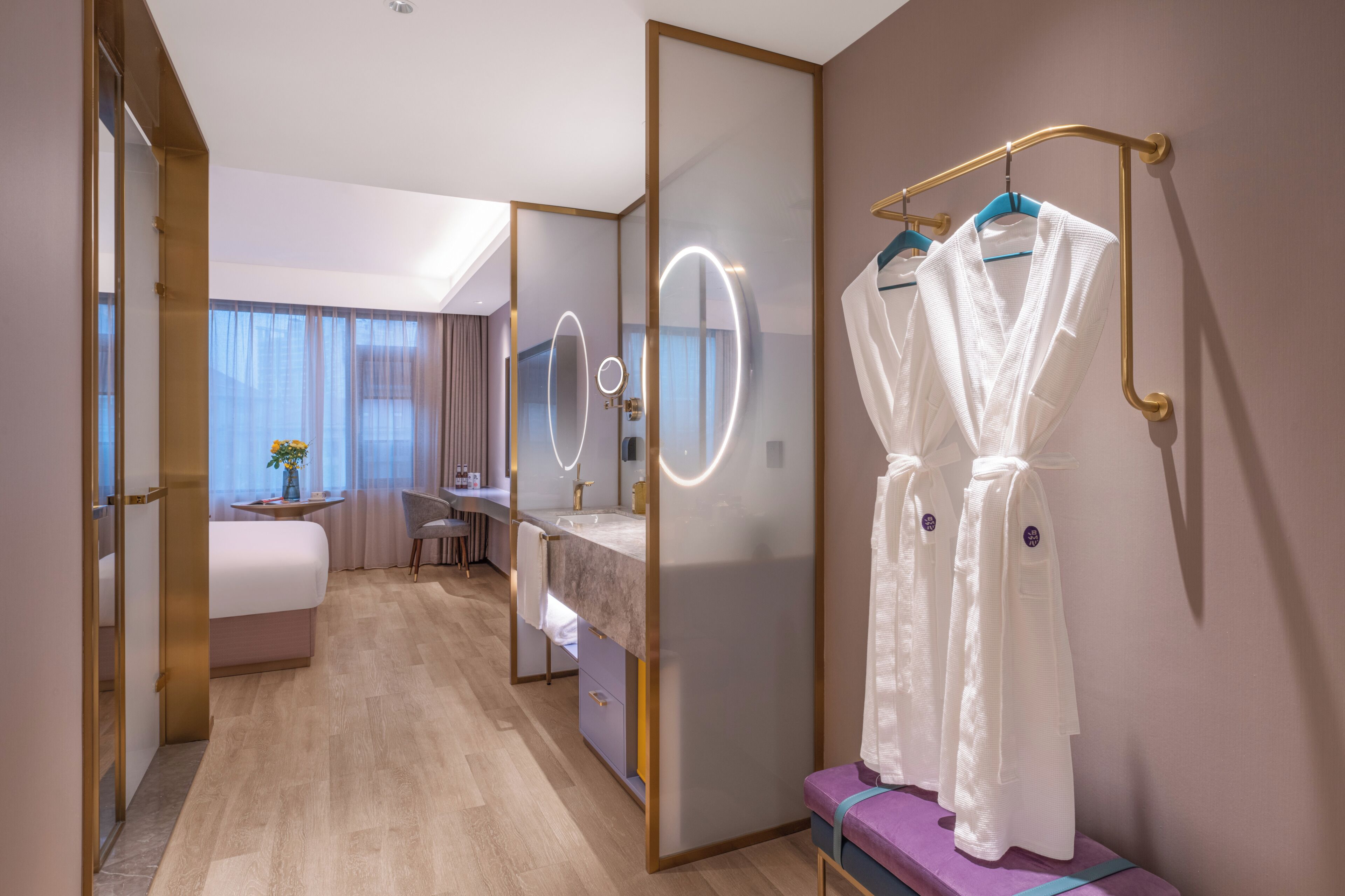 Habitación de hotel con una cama, un tocador con espejo y un perchero para bata.