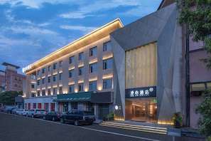 Un hotel con fachada moderna, varios pisos y una entrada destacada.