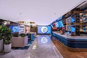 Zona de bar moderna con asientos, una pantalla digital y una barra repleta de botellas.