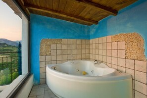 Een badkamer met een bad, blauwe wanden en uitzicht op het landschap.