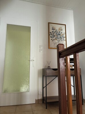 A room with a white door, a small table with a vase and a candle, and a framed artwork on the wall. - Along the Rhône, amid vineyards and fine dining (Serves-sur-Rhône)