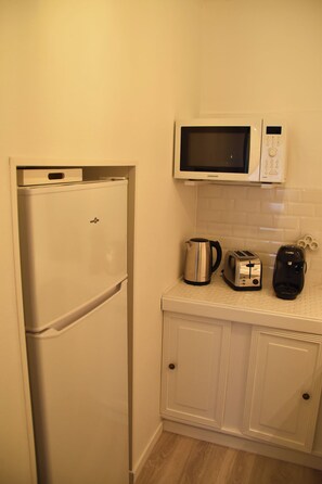 A compact kitchen with a white refrigerator, a microwave, a kettle, a toaster, and a coffee maker on the countertop. - Along the Rhône, amid vineyards and fine dining (Serves-sur-Rhône)