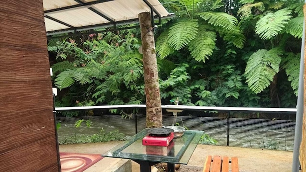 Un'area salotto esterna con un tavolo in vetro, un oggetto rosso sopra e una panchina in legno.