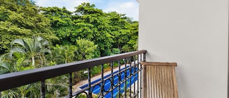 A balcony with a view of a swimming pool and lush greenery.