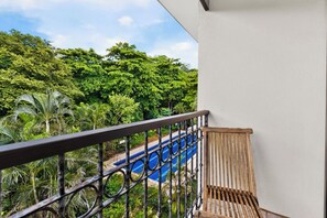 A balcony with a view of a swimming pool and lush greenery. - The Oaks Tamarindo Luxury Condo (Villareal)
