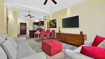 A living room with a sofa, ottoman, and a television mounted on the wall.