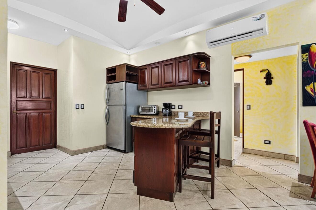 Una cocina con armarios de madera, un refrigerador, un microondas y una cafetera.