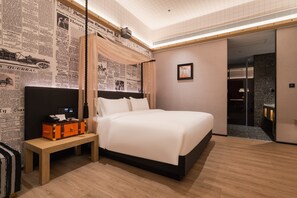 Ett hotellrum med en stor säng, ett nattduksbord med en lampa och en vägg som är dekorerad med utklippta tidningsartiklar.