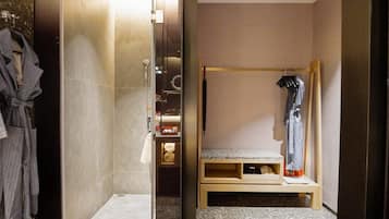 A modern bathroom with a shower, a robe rack, and a bench.