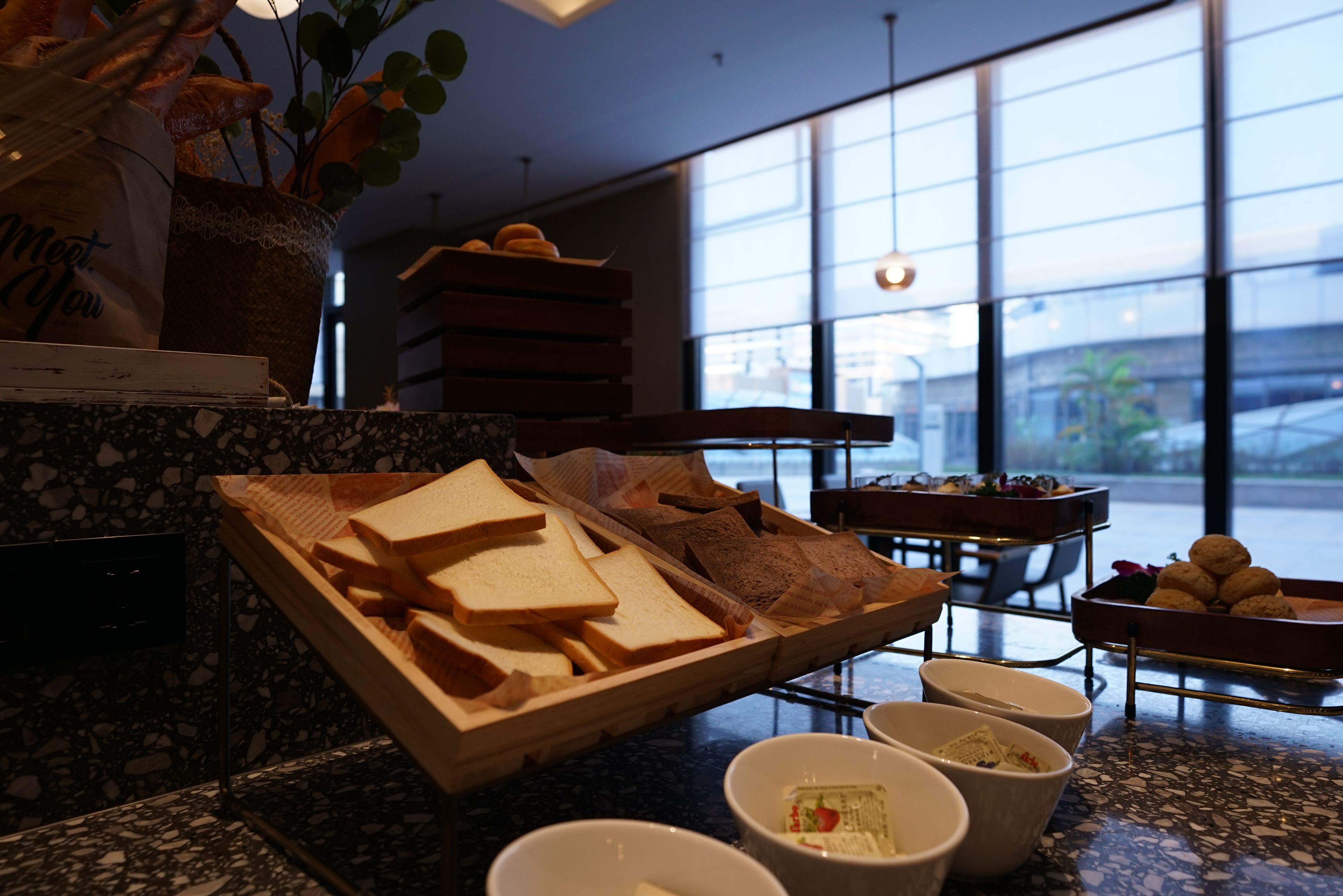 A buffet setup with bread, butter, and condiments on a marble countertop.