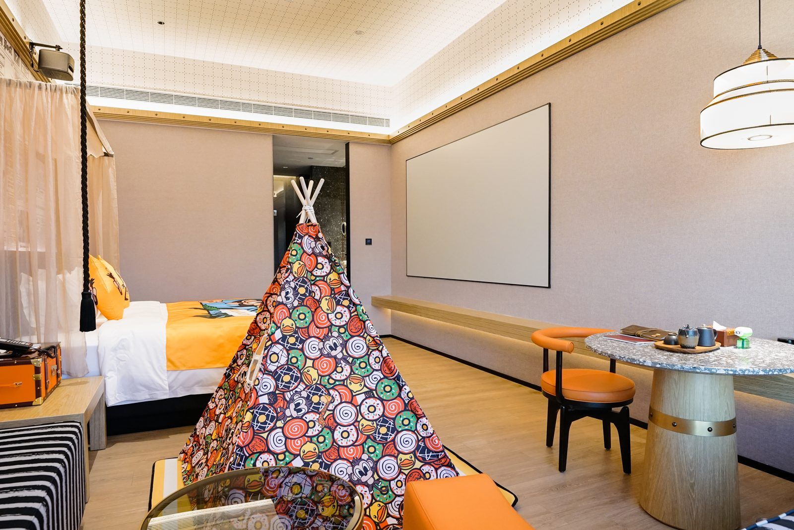 Une chambre d’hôtel avec un lit, une petite table et des chaises, un mur décoratif et une grande fenêtre.