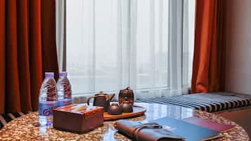 Une chambre d’hôtel avec une table ronde sur laquelle sont disposés une théière, deux bouteilles d’eau, une boîte de mouchoirs et un carnet.