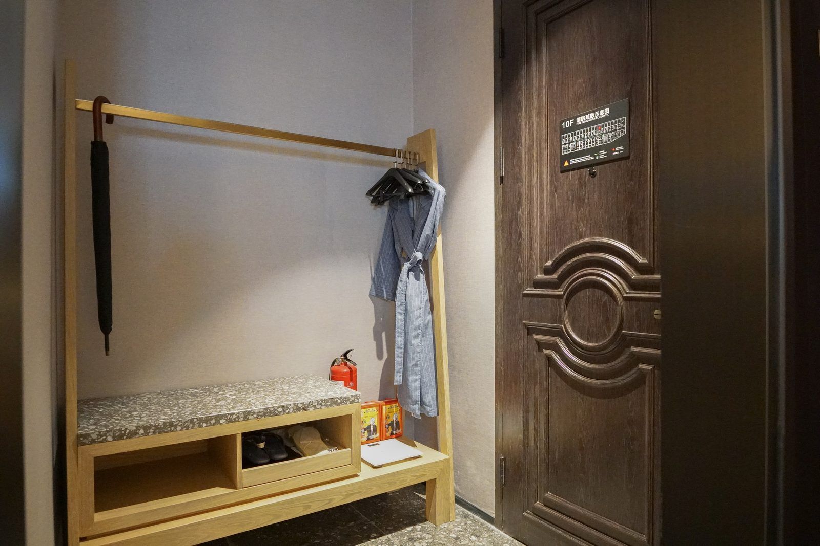 A bunk bed with a wooden frame, a small table, and a fire extinguisher. A wooden door with a circular design is visible.
