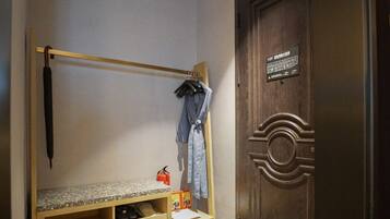 A bunk bed with a wooden frame, a small table, and a fire extinguisher. A wooden door with a circular design is visible.