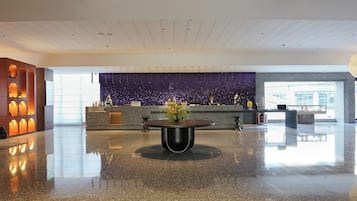 Un vestíbulo amplio con piso pulido, una recepción y una pared decorativa con diseño de estrellas.
