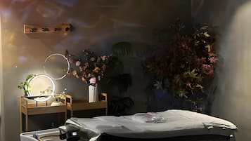 Una habitación moderna con cama, mesita de noche y un espejo montado en la pared.