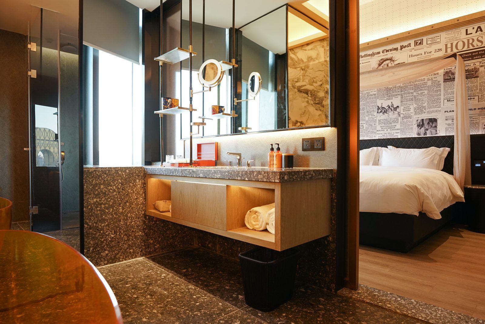 Un baño moderno con tocador, un espejo grande y una cama en la habitación contigua.