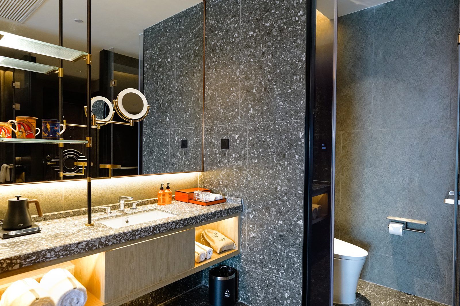 Une salle de bain moderne avec un comptoir en granit, un grand miroir et des toilettes.