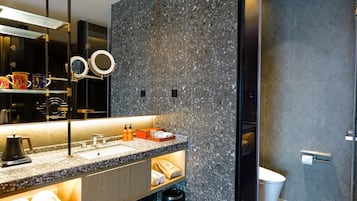 Une salle de bain moderne avec un comptoir en granit, un grand miroir et des toilettes.
