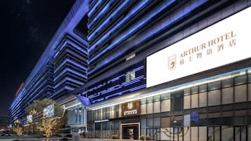 A modern Arthur Hotel with a prominent sign, large windows, and a well-lit facade.