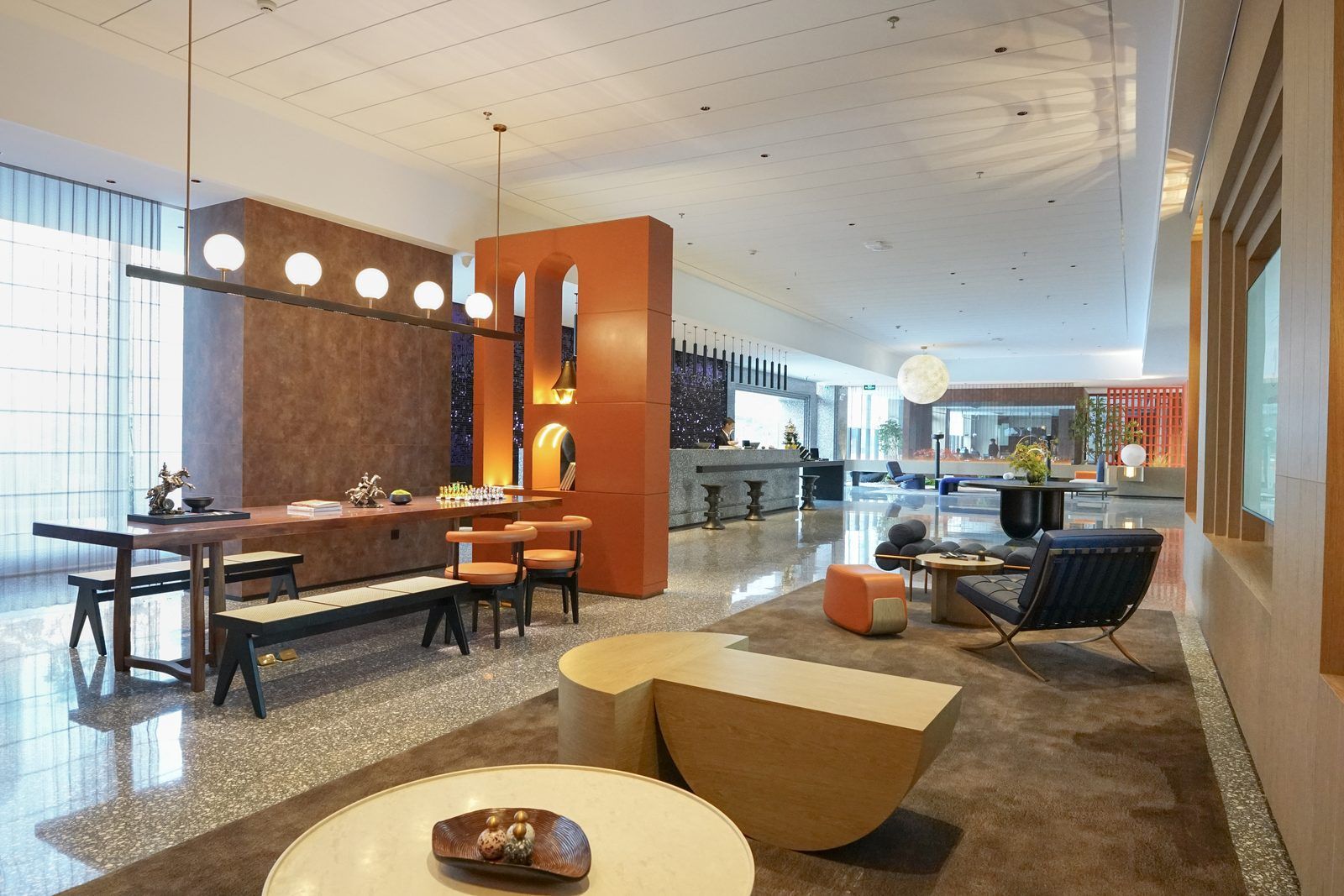 Un moderno vestíbulo de hotel con un mostrador de recepción, zona de estar y un bar.